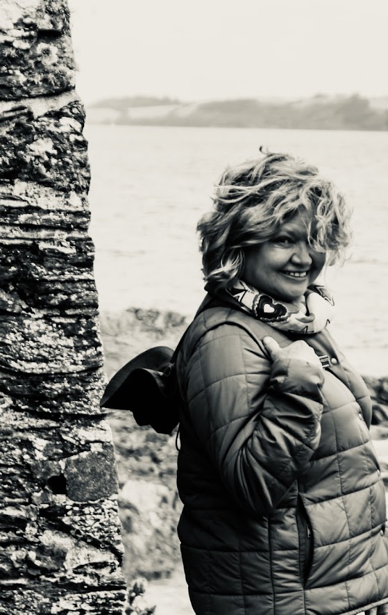 Windswept smiling Ceciel posing by granit wall with the sea in the background