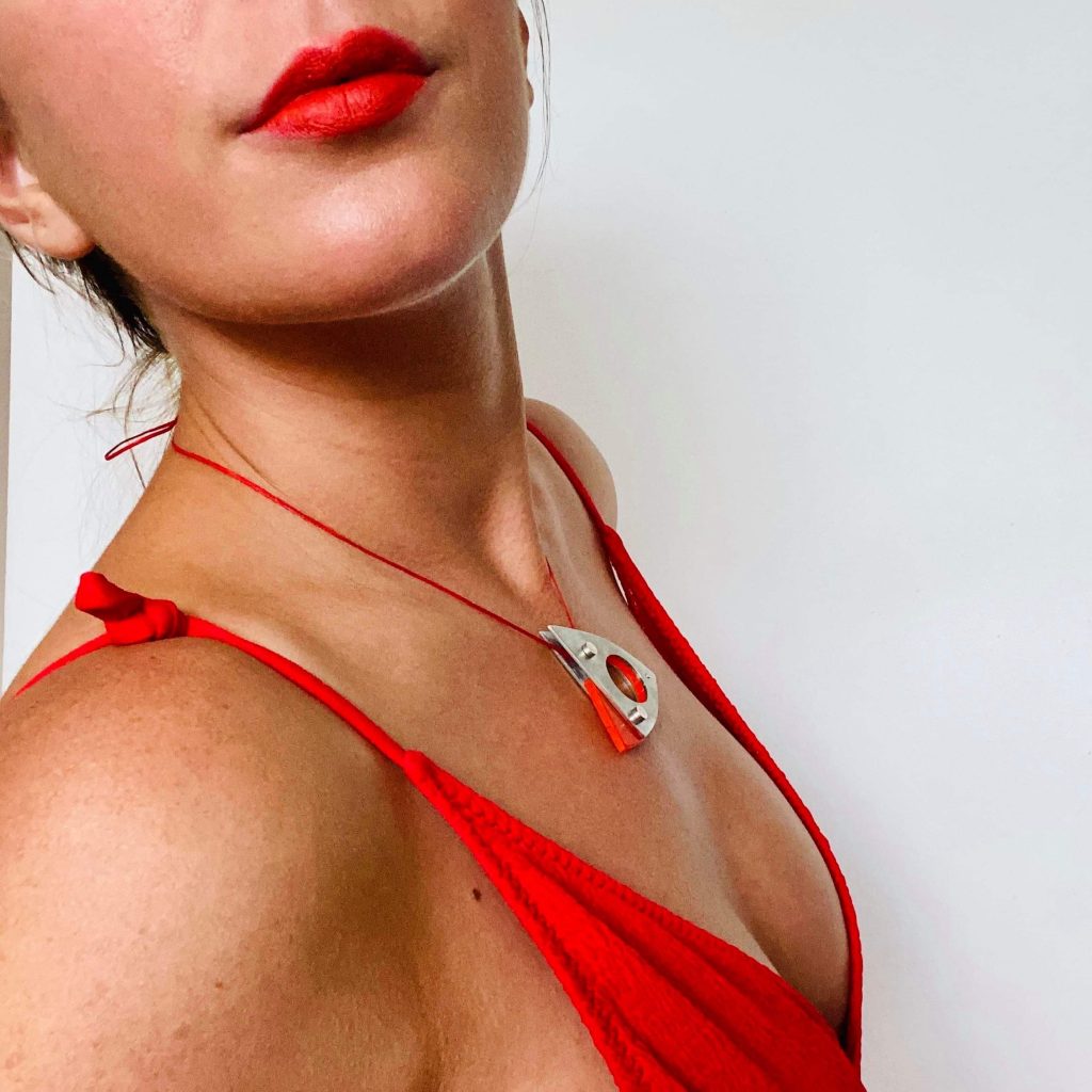 model wearing orange low cut dress with pewter and orange pendant