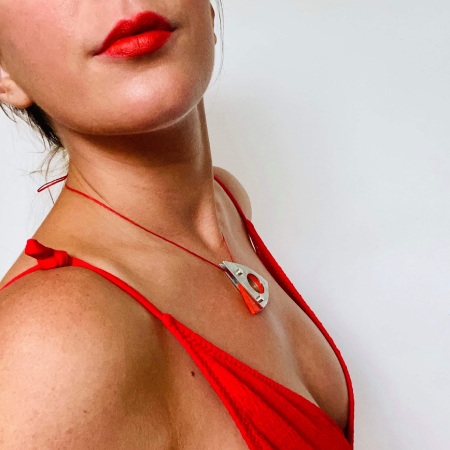 model wearing orange low cut dress with orange Dhoek pendant