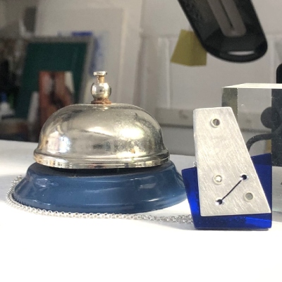 Hebbe pendant blue with cut out slit on front next to retro shop bell on counter in Gallery